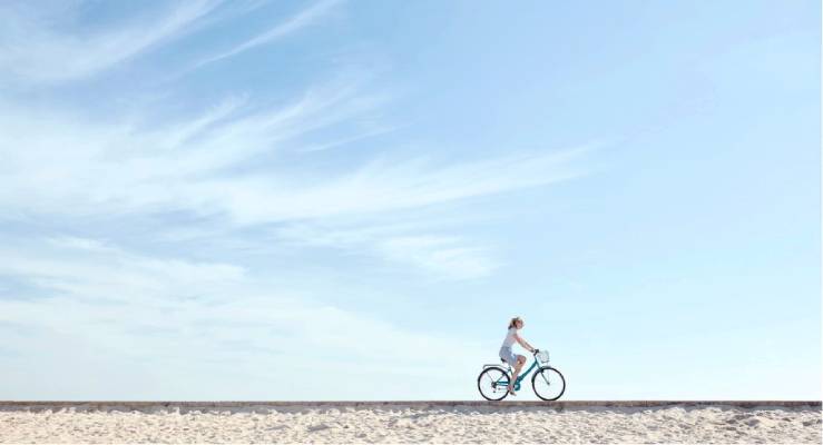 foto aesthetic keren cewek naik sepeda dengan latar langit biru