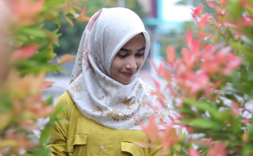Cewek manis pakai Hijab Foto model di taman dengan tanaman Pucuk Merah