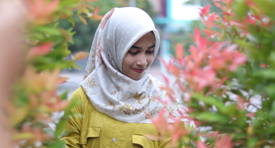Cewek manis pakai Hijab Foto model di taman dengan tanaman Pucuk Merah